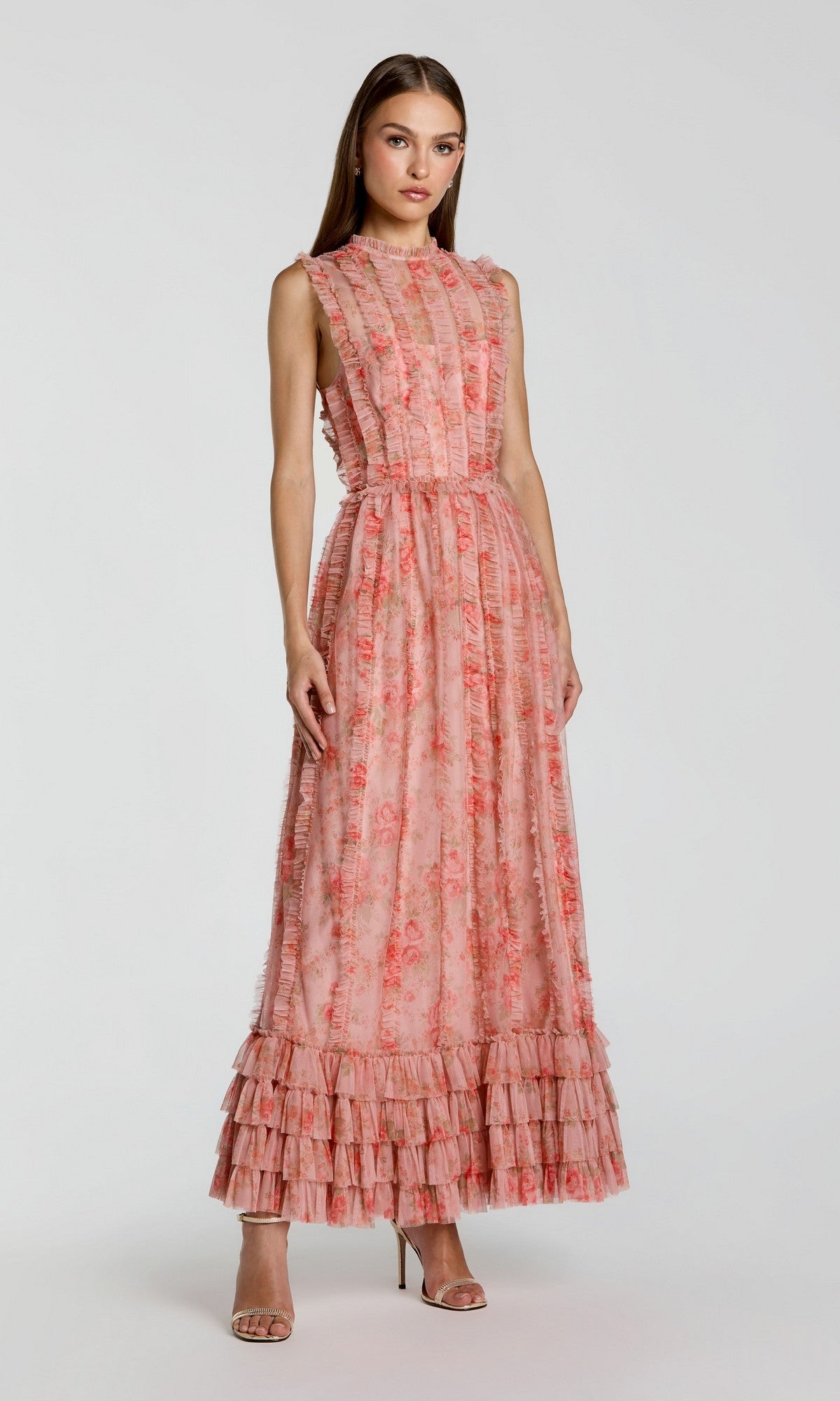 A woman wearing the Mac Duggal 8309 long formal dress in rose multi, with a sleeveless design and floral ruffle accents, stands in open-toe high heels against a plain light background.